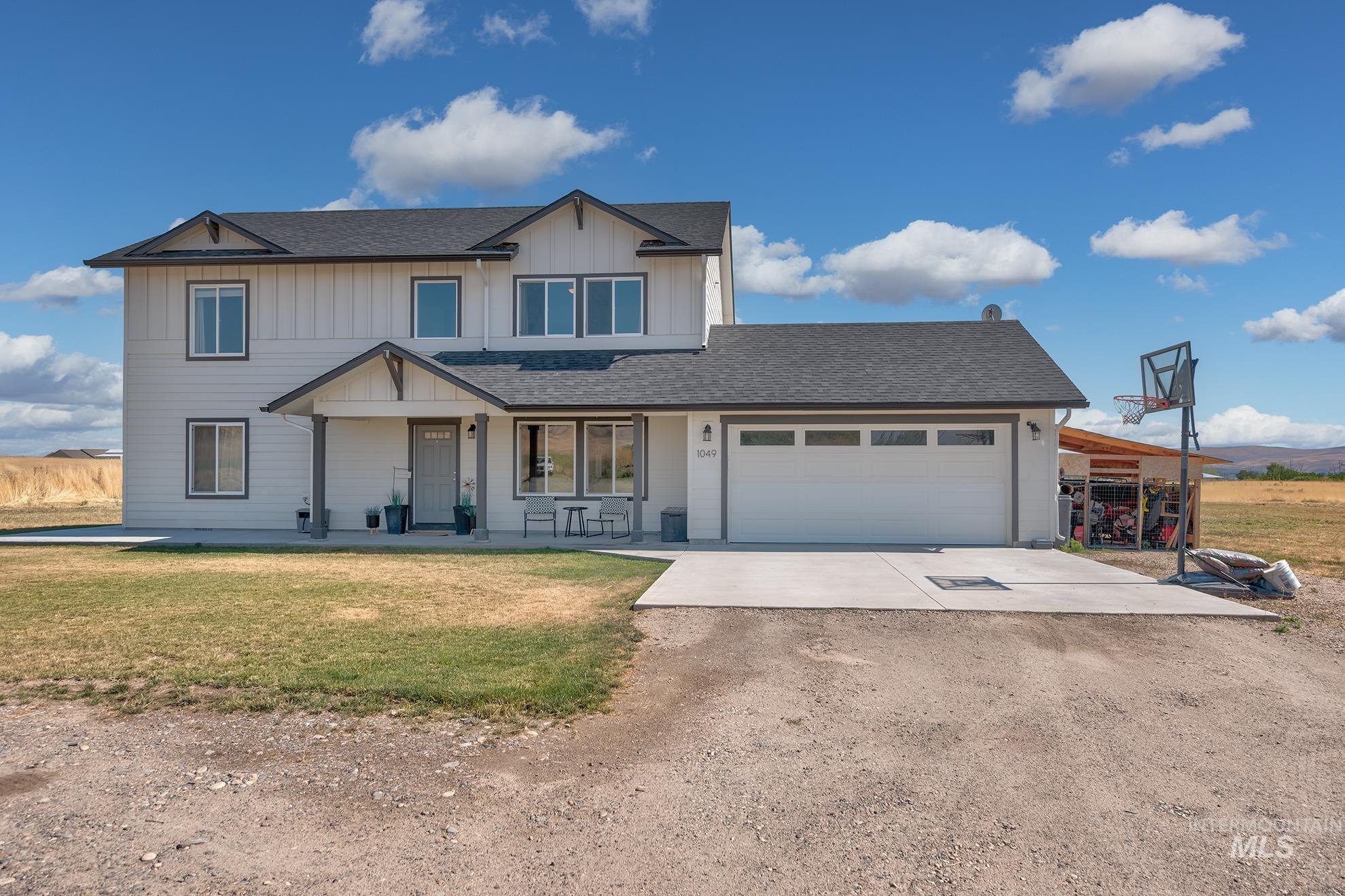 1049 Price Road Weiser, ID 83672 - Photo 1 of 47 Two-story residence featuring light-colored vertical panel siding with dark trim accents