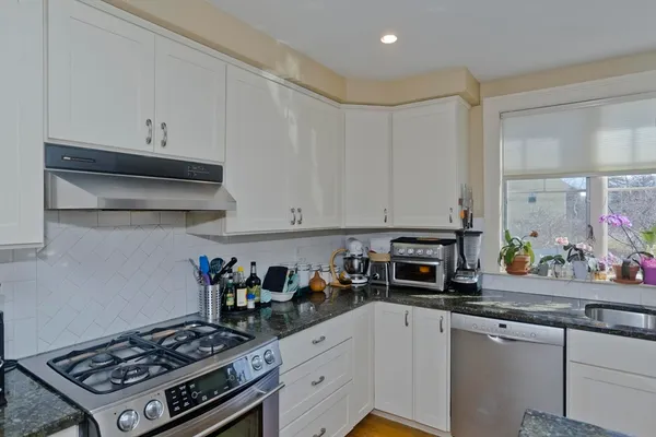 a kitchen with stainless steel appliances a stove a white cabinets and a sink