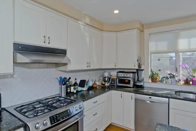 a kitchen with stainless steel appliances a stove a white cabinets and a sink