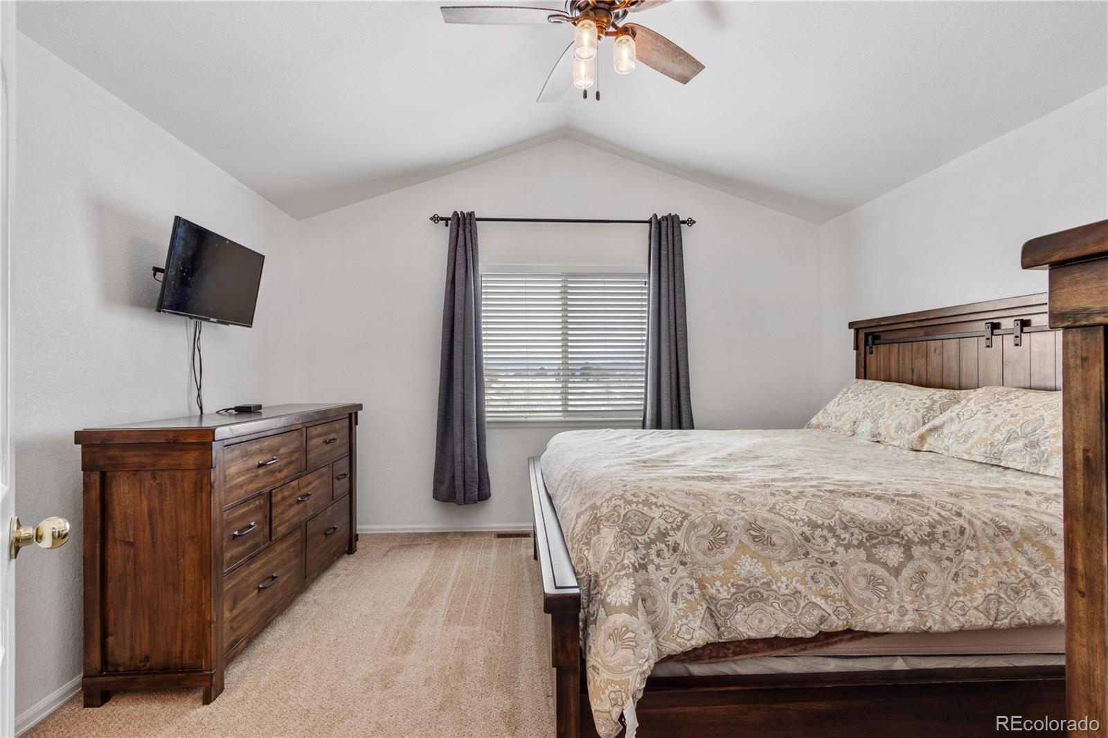 5405 Wolf Street Frederick, CO 80504 - Photo 18 of 36 a bedroom with a bed and a flat tv screen on dresser