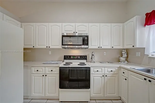a kitchen with white cabinets and appliances