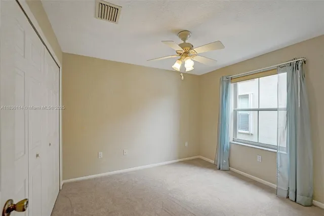 an empty room with windows and fan