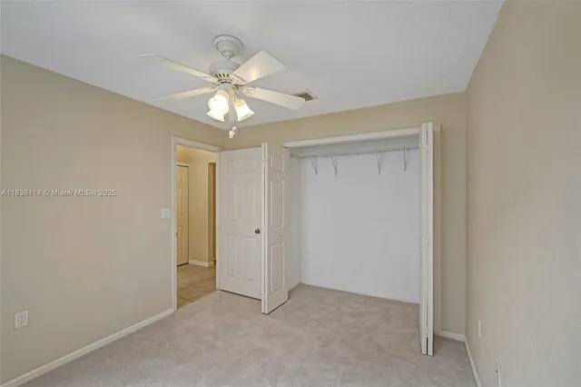 a view of an empty room and chandelier fan