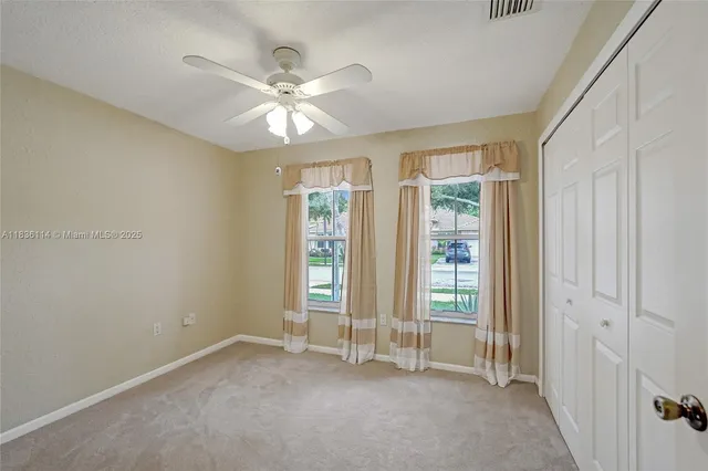 an empty room with windows and fan