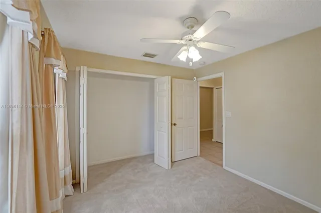 a view of an empty room and chandelier fan