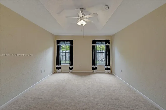 an empty room with windows and ceiling fan