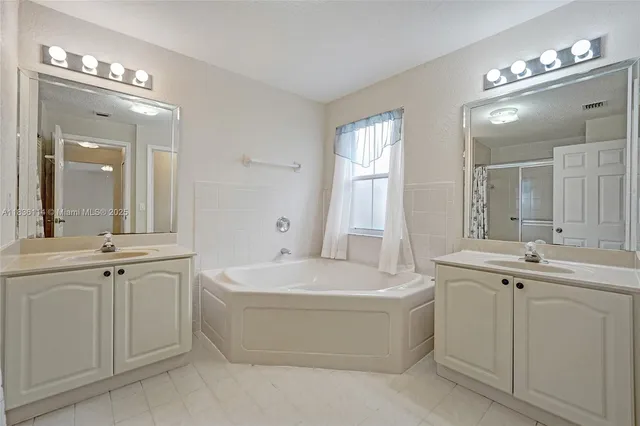 a spacious bathroom with a tub a sink and mirror