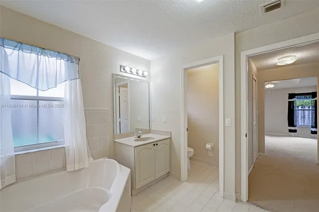 a bathroom with a tub sink and mirror