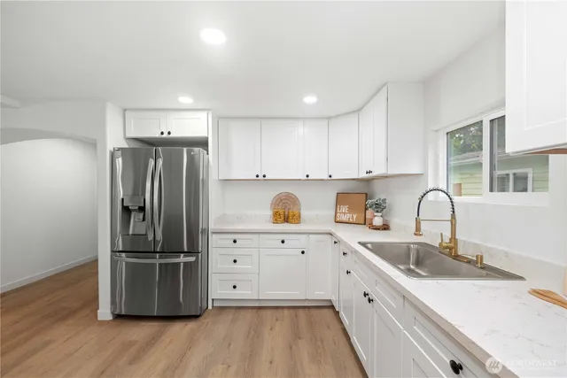 a kitchen with stainless steel appliances granite countertop a refrigerator sink and white cabinets