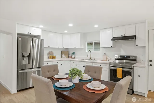 a kitchen with stainless steel appliances stove refrigerator dining table and chairs