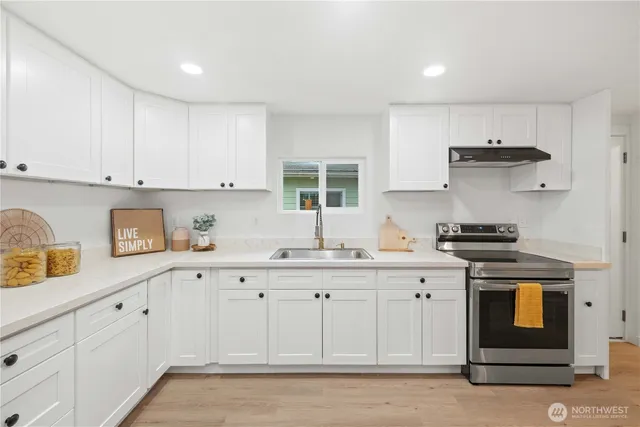 a kitchen with granite countertop white cabinets and stainless steel appliances