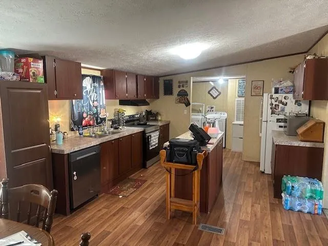 a open kitchen with stainless steel appliances granite countertop a stove refrigerator and a dining table with wooden floor