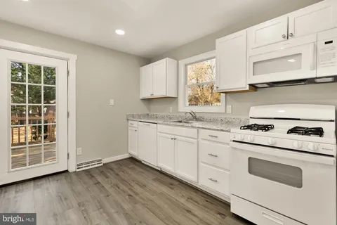 a kitchen with stainless steel appliances granite countertop a stove a sink and white cabinets