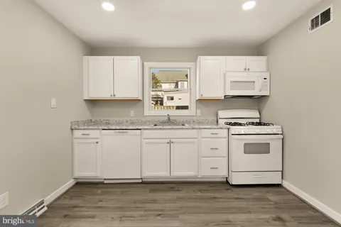 a kitchen with granite countertop white cabinets and white appliances