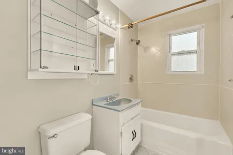 a bathroom with a granite countertop sink a toilet and shower