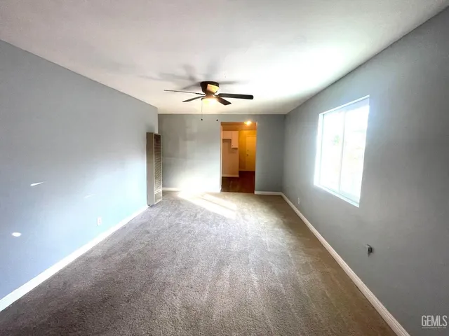 an empty room with windows and ceiling fan