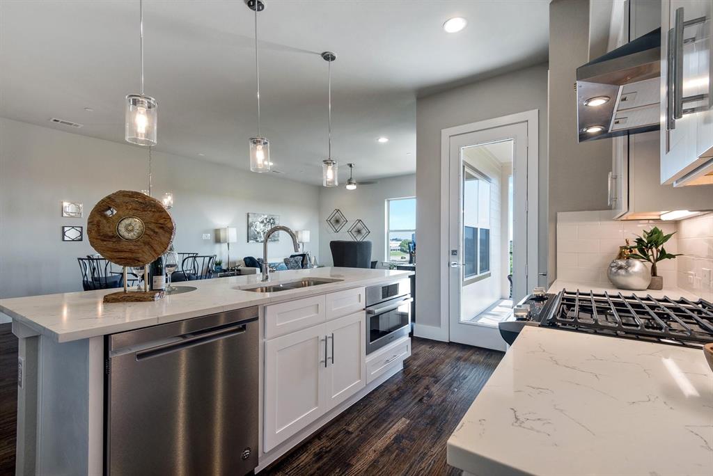 770 North Plano Road, Unit 303 Richardson, TX 75081 - Photo 7 of 26 Modern kitchen featuring white cabinetry, stainless steel appliances, a gas range, and a spacious island with a sink and pendant lighting