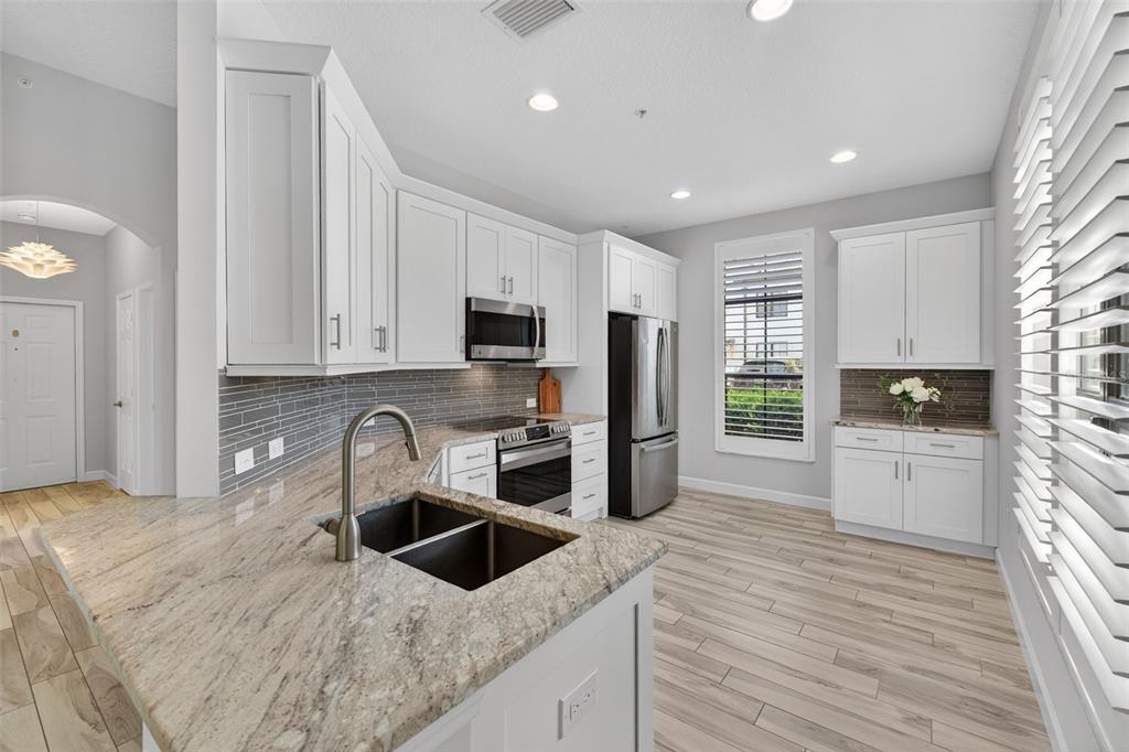 701 Westpark Way, Unit 101 Celebration, FL 34747 - Photo 7 of 69 a kitchen with granite countertop a sink stainless steel appliances and white cabinets
