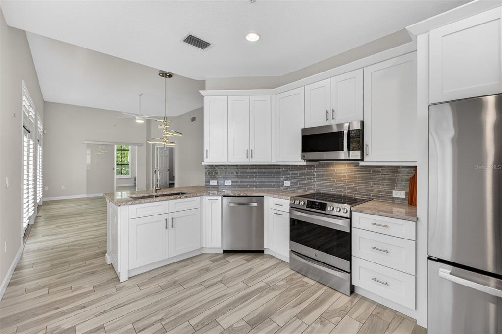 701 Westpark Way, Unit 101 Celebration, FL 34747 - Photo 8 of 69 a kitchen with granite countertop white cabinets and stainless steel appliances