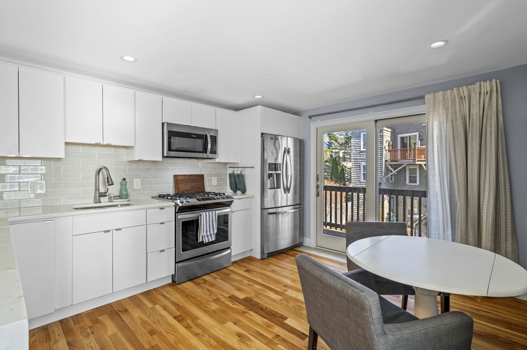 9 Hanover Court, Unit 1 Marblehead, MA 01945 - Photo 9 of 38 a kitchen with stainless steel appliances granite countertop a stove top oven a sink dishwasher a refrigerator and a dining table with wooden floor
