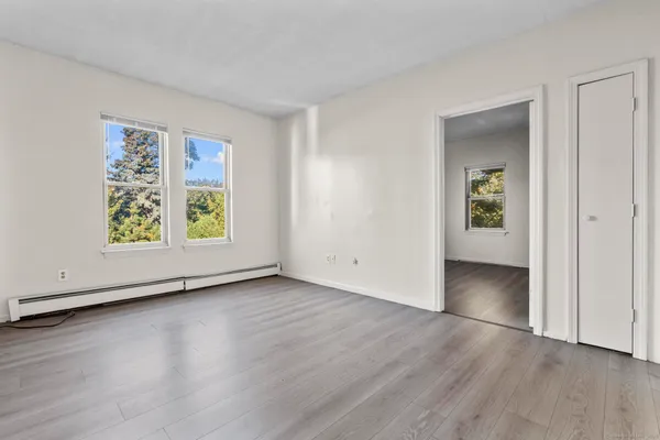an empty room with wooden floor and windows