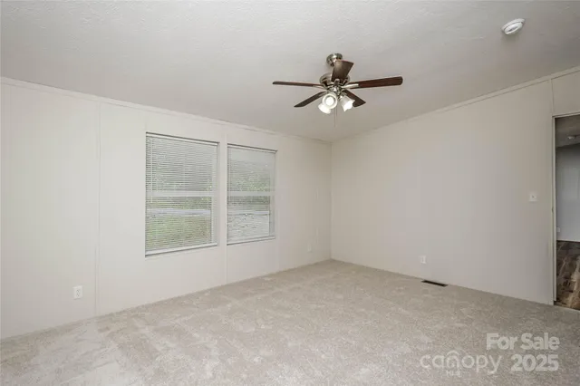 an empty room with a window and a fan