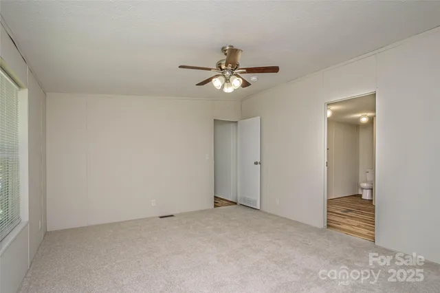 an empty room with closet and a ceiling fan