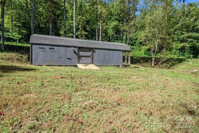 a backyard of a house with large trees and wooden fence