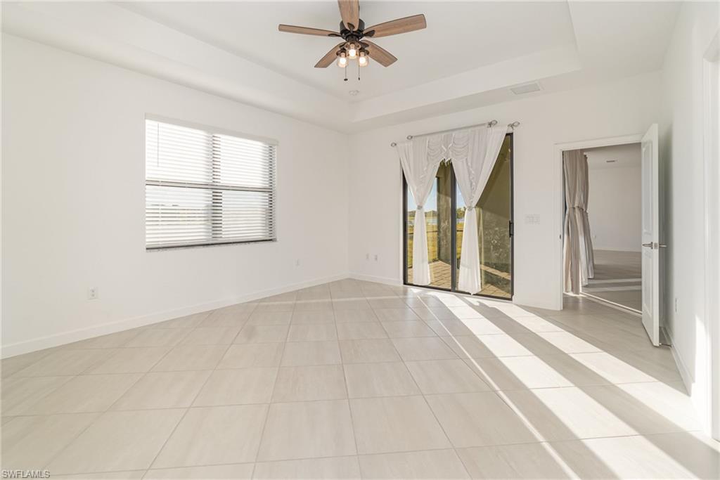 11127 Canopy Loop Fort Myers, FL 33913 - Photo 7 of 29 Unfurnished room featuring light tile patterned floors, a ceiling fan, and a tray ceiling