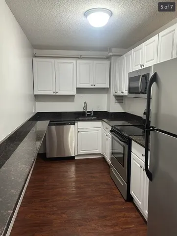 a kitchen with granite countertop a sink stainless steel appliances and cabinets