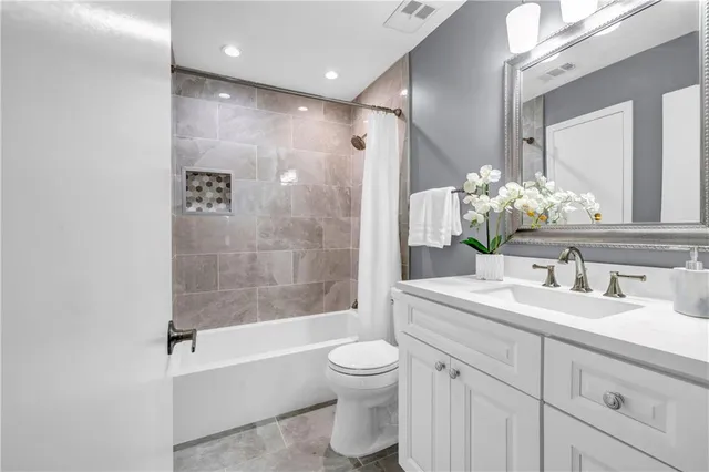 a bathroom with a granite countertop sink toilet a large mirror a bathtub and shower
