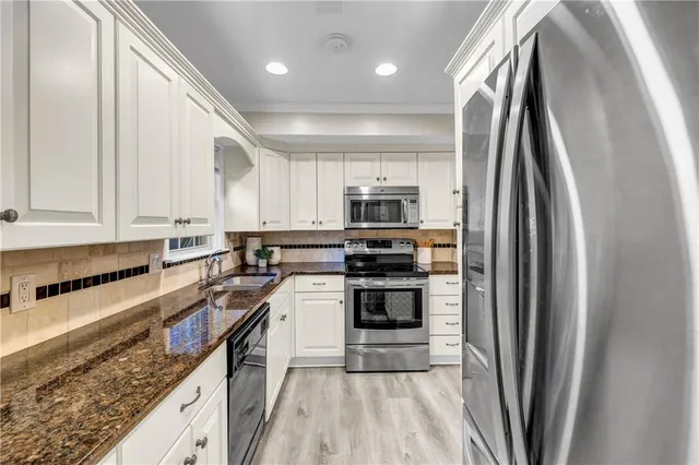 a kitchen with stainless steel appliances granite countertop a refrigerator a stove and a sink