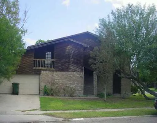 a view of a house with a yard and large tree