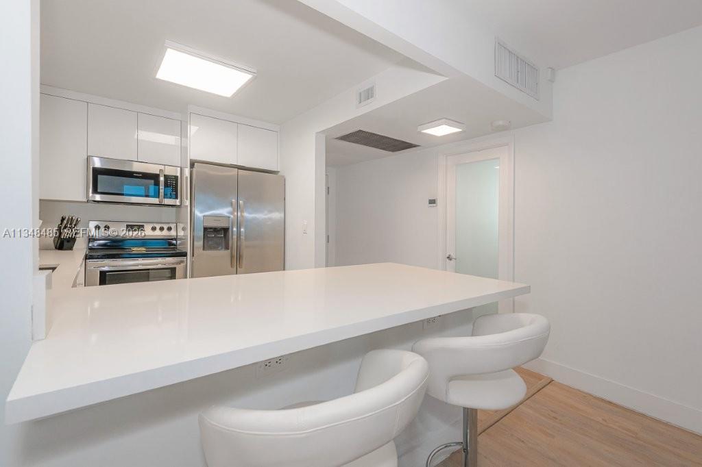 2301 Collins Avenue, Unit 927 Miami Beach, FL 33139 - Photo 18 of 30 a large kitchen with a table and stainless steel appliances