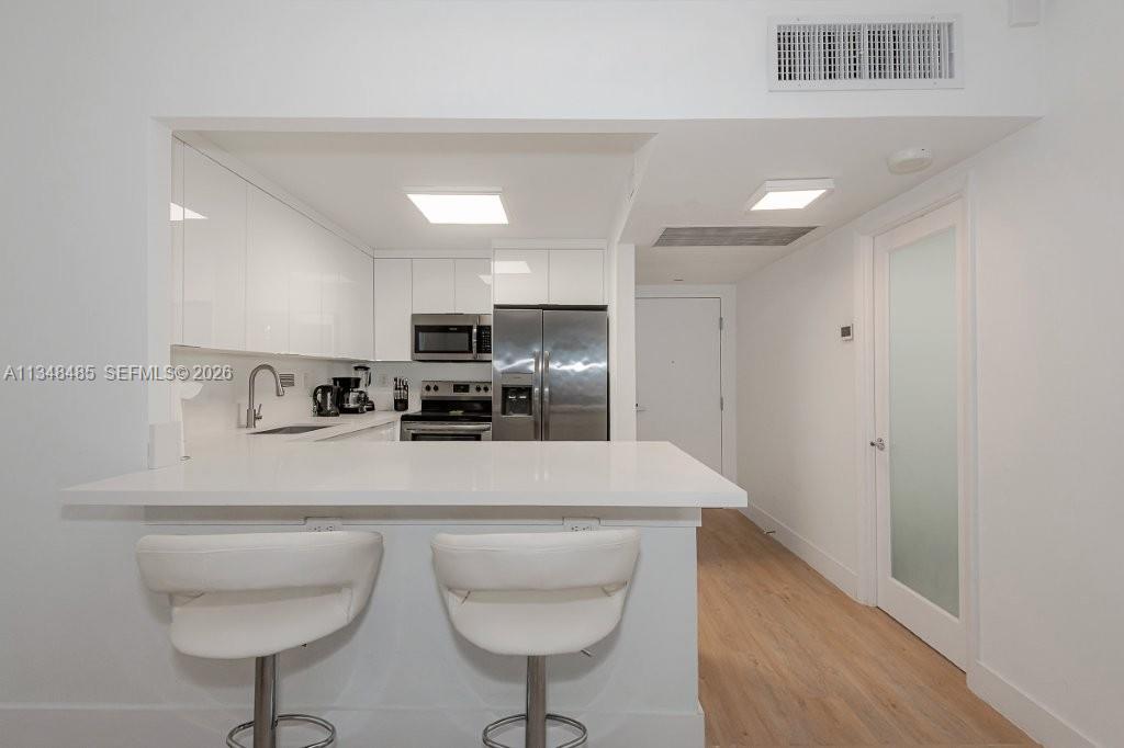 2301 Collins Avenue, Unit 927 Miami Beach, FL 33139 - Photo 23 of 30 a kitchen with stainless steel appliances a sink a stove a refrigerator cabinets and wooden floor
