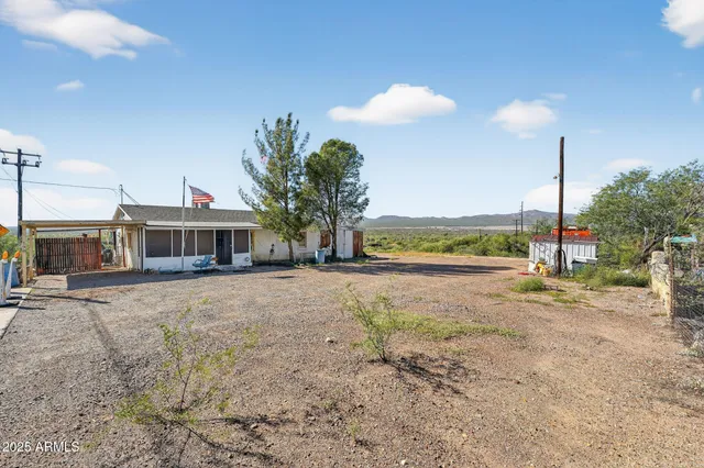 a view of a house with a yard and a car park in front of it