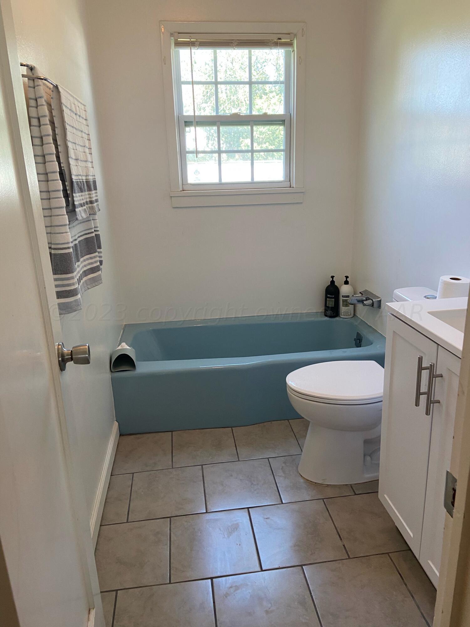 720 Santa Fe Avenue Channing, TX 79018 - Photo 14 of 23 a bathroom with a toilet a sink a window and a mirror