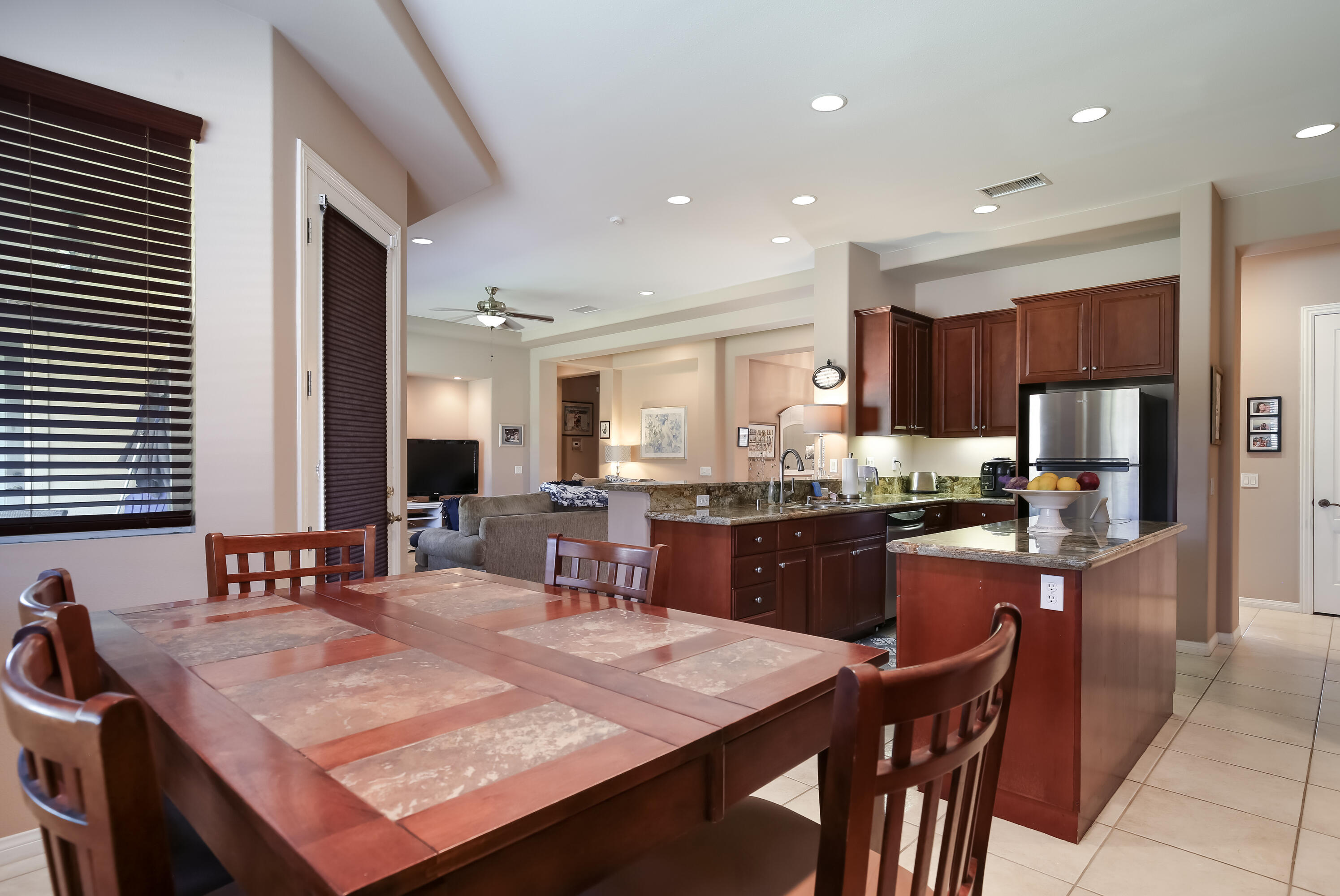 153 Bellini Way Palm Desert, CA 92211 - Photo 14 of 26 a kitchen with stainless steel appliances kitchen island granite countertop a sink a stove a refrigerator a dining table and chairs