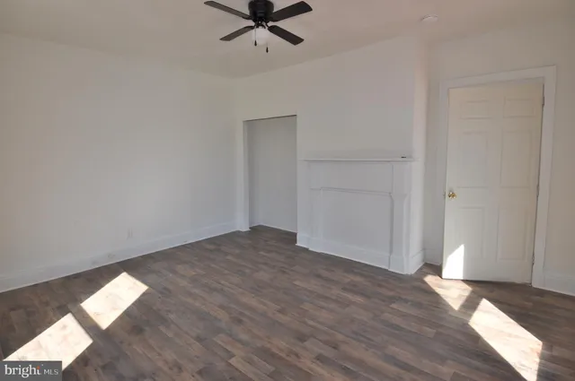 an empty room with wooden floor closet and windows