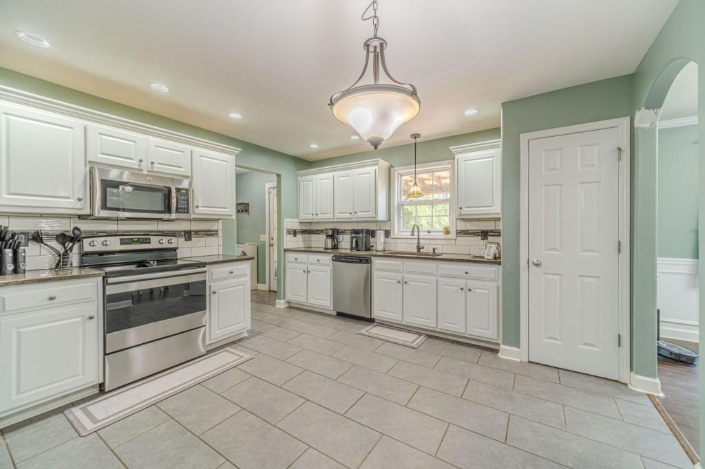536 San Dra Way Monroe, GA 30656 - Photo 12 of 30 a kitchen with stainless steel appliances granite countertop a stove and white cabinets