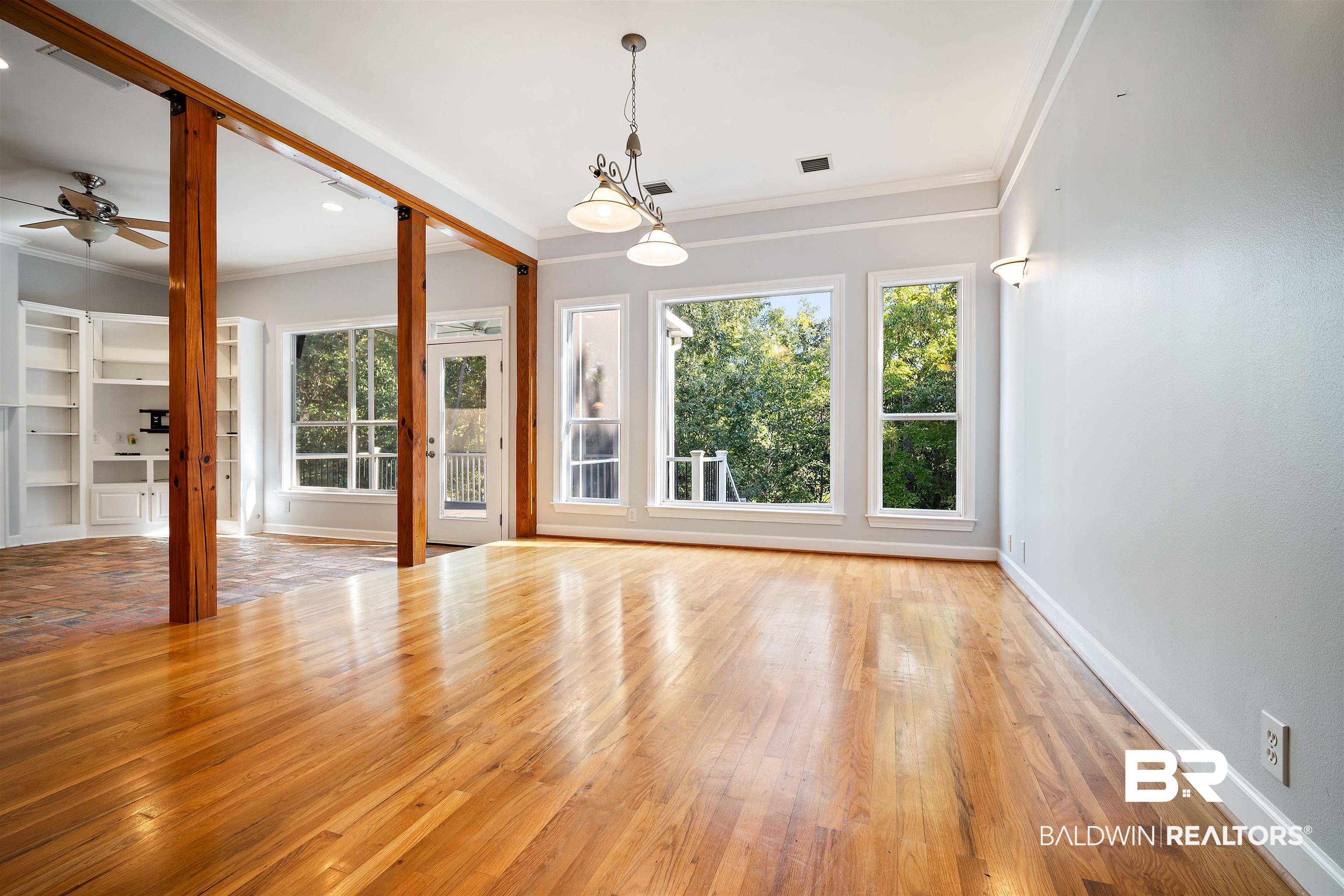 204 General Canby Loop Daphne, AL 36527 - Photo 3 of 36 Unfurnished room with ceiling fan with notable chandelier, ornamental molding, light wood-type flooring, and a healthy amount of sunlight