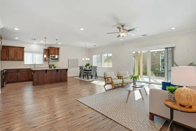 a living room with furniture kitchen view and a wooden floor