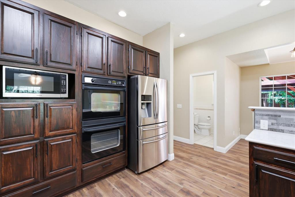 289 County Road 1170 Decatur, TX 76234 - Photo 15 of 40 Kitchen featuring abundant dark wood cabinetry, stainless steel microwave, double wall ovens, stainless steel refrigerator, and wood-finish flooring