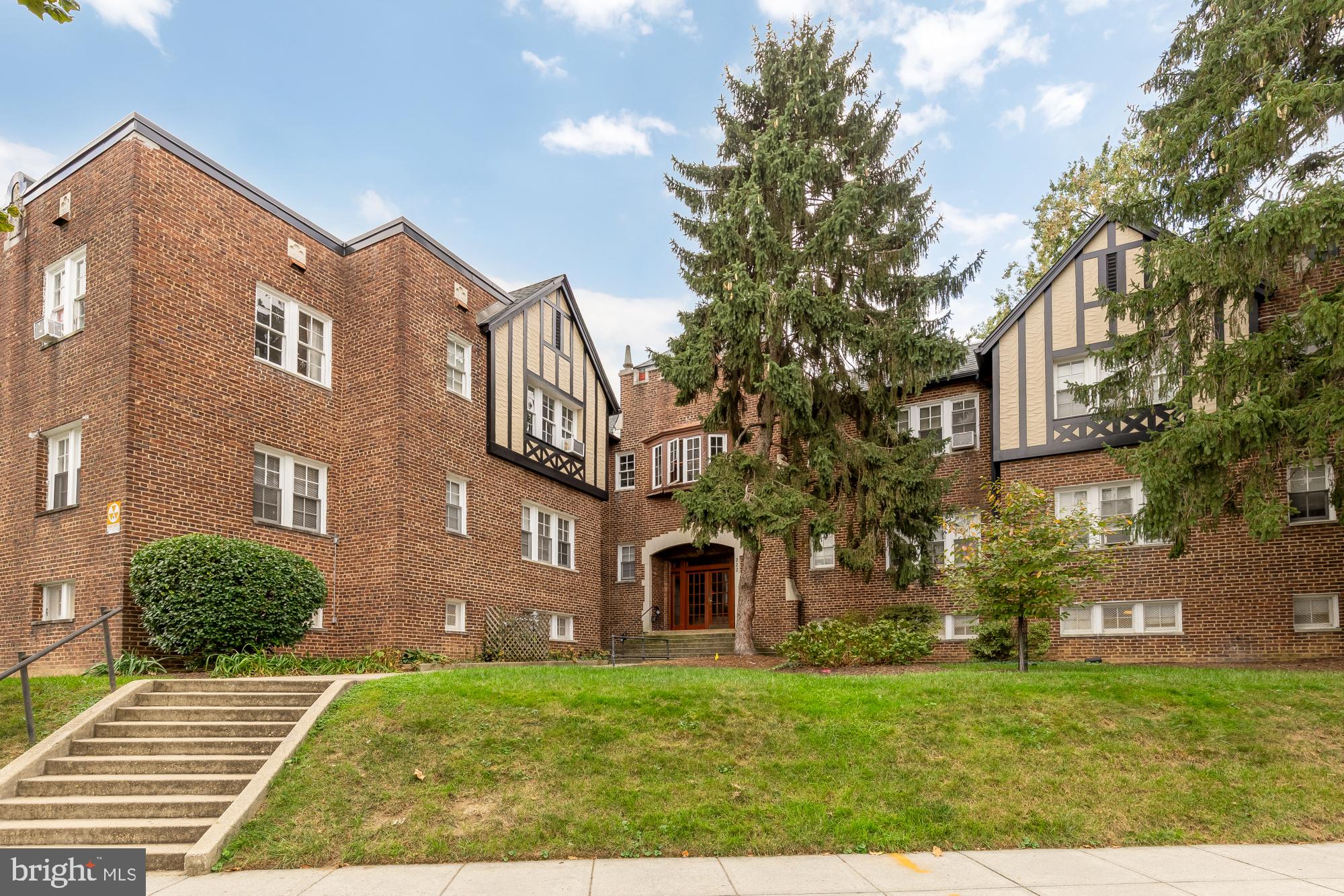 a view of a yard in front of a brick house with a large tree