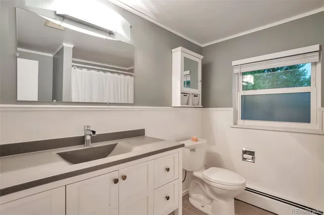 a bathroom with a toilet a sink a mirror and a window