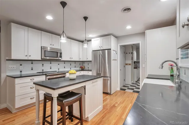 a kitchen with stainless steel appliances granite countertop a stove a refrigerator a sink dishwasher a dining table and chairs with wooden floor