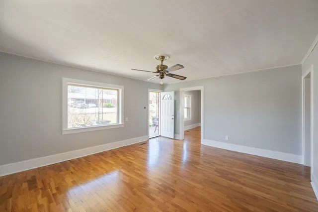 a view of empty room with wooden floor and fan