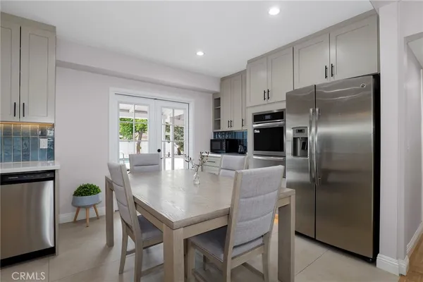 a kitchen with stainless steel appliances granite countertop a refrigerator a stove a kitchen island a dining table and chairs with wooden floor