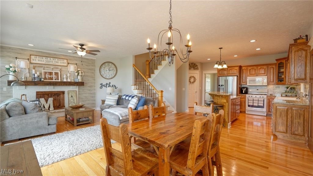 66333 Read Road Cambridge, OH 43725 - Photo 28 of 49 Dining room featuring ceiling fan with notable chandelier, a fireplace, and light wood-type flooring