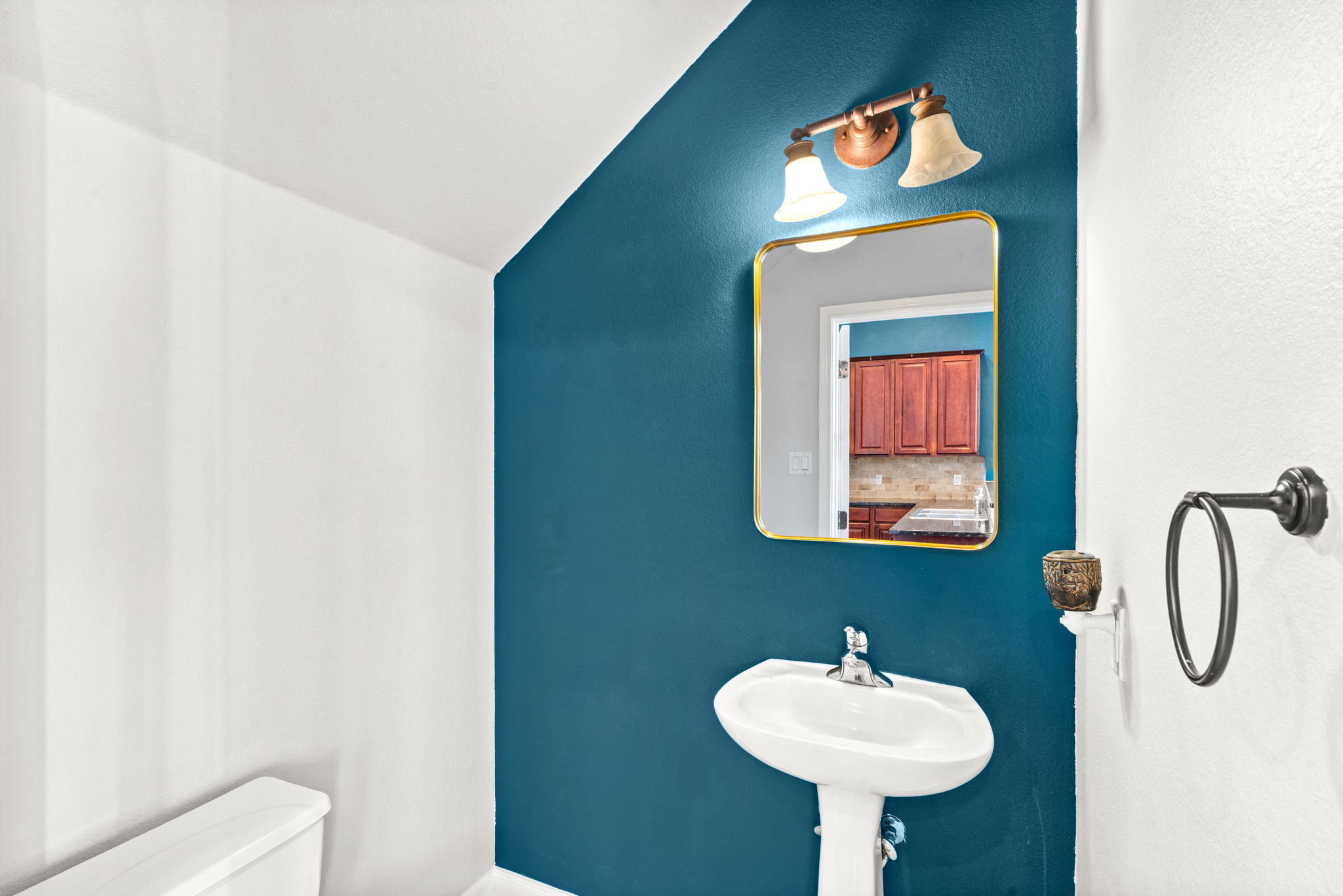 6704 Menchaca Road, Unit 42 Austin, TX 78745 - Photo 8 of 21 A compact powder room with a sleek pedestal sink and contemporary mirror reflects the adjoining kitchen.